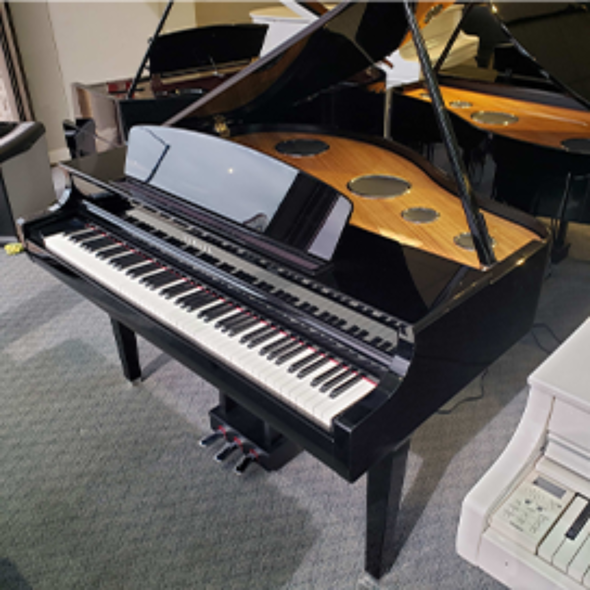 Black grand piano in showroom with glossy finish and open lid, surrounded by other pianos.