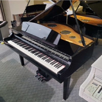 Black grand piano in showroom with glossy finish and open lid, surrounded by other pianos.