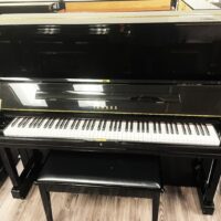 Black Yamaha upright piano with polished finish in a showroom setting.