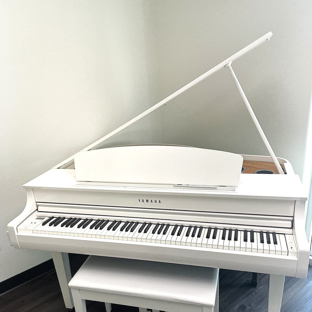 White Yamaha digital piano with a sleek design, featuring weighted keys and a matching bench for optimal playability.