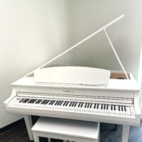 White Yamaha digital piano with a sleek design, featuring weighted keys and a matching bench for optimal playability.