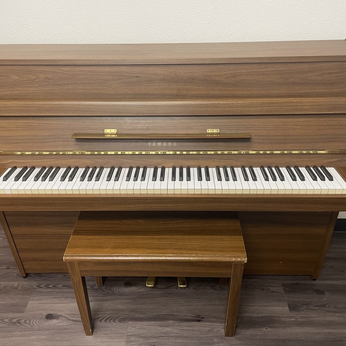 Yamaha upright piano in walnut finish with 88 weighted keys and matching bench, ideal for home practice and performance.
