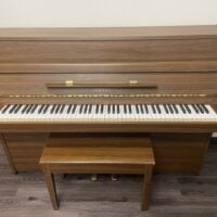 Yamaha upright piano in walnut finish with 88 weighted keys and matching bench, ideal for home practice and performance.