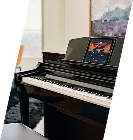 Digital grand piano with touchscreen in a modern showroom setting.