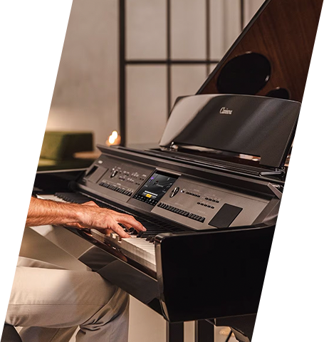 Man playing a black digital grand piano in a modern showroom.